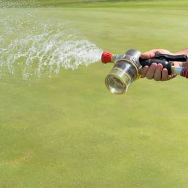 Hand-watering a green on a golf course.