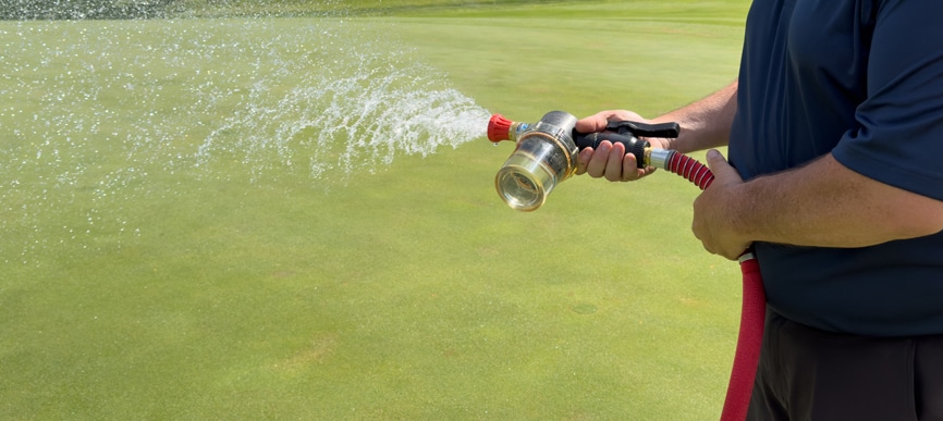 Hand-watering a green on a golf course.